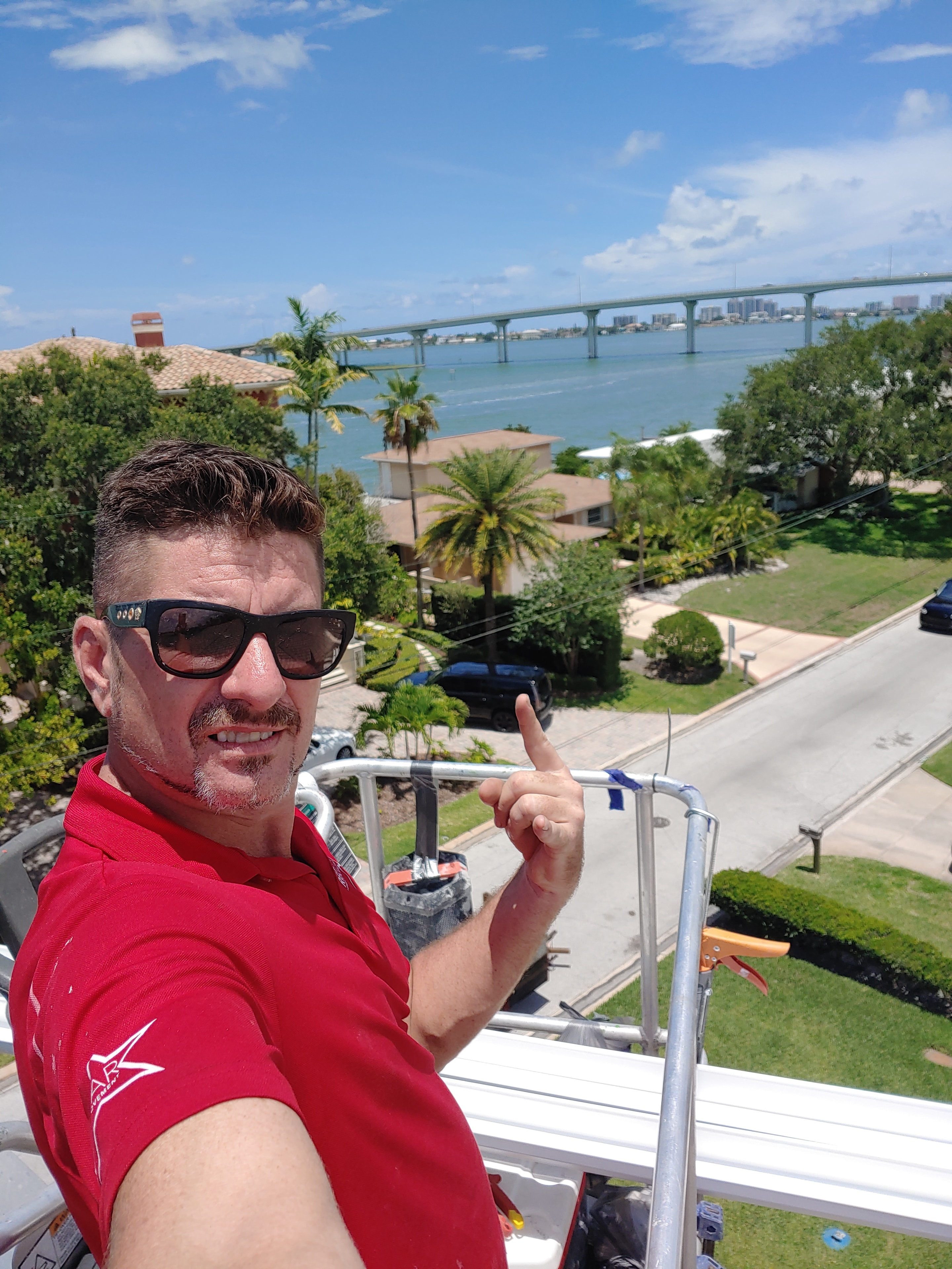 Two Red Star crew members on ladders working on a luxury home entrance with ornate columns and palm trees.