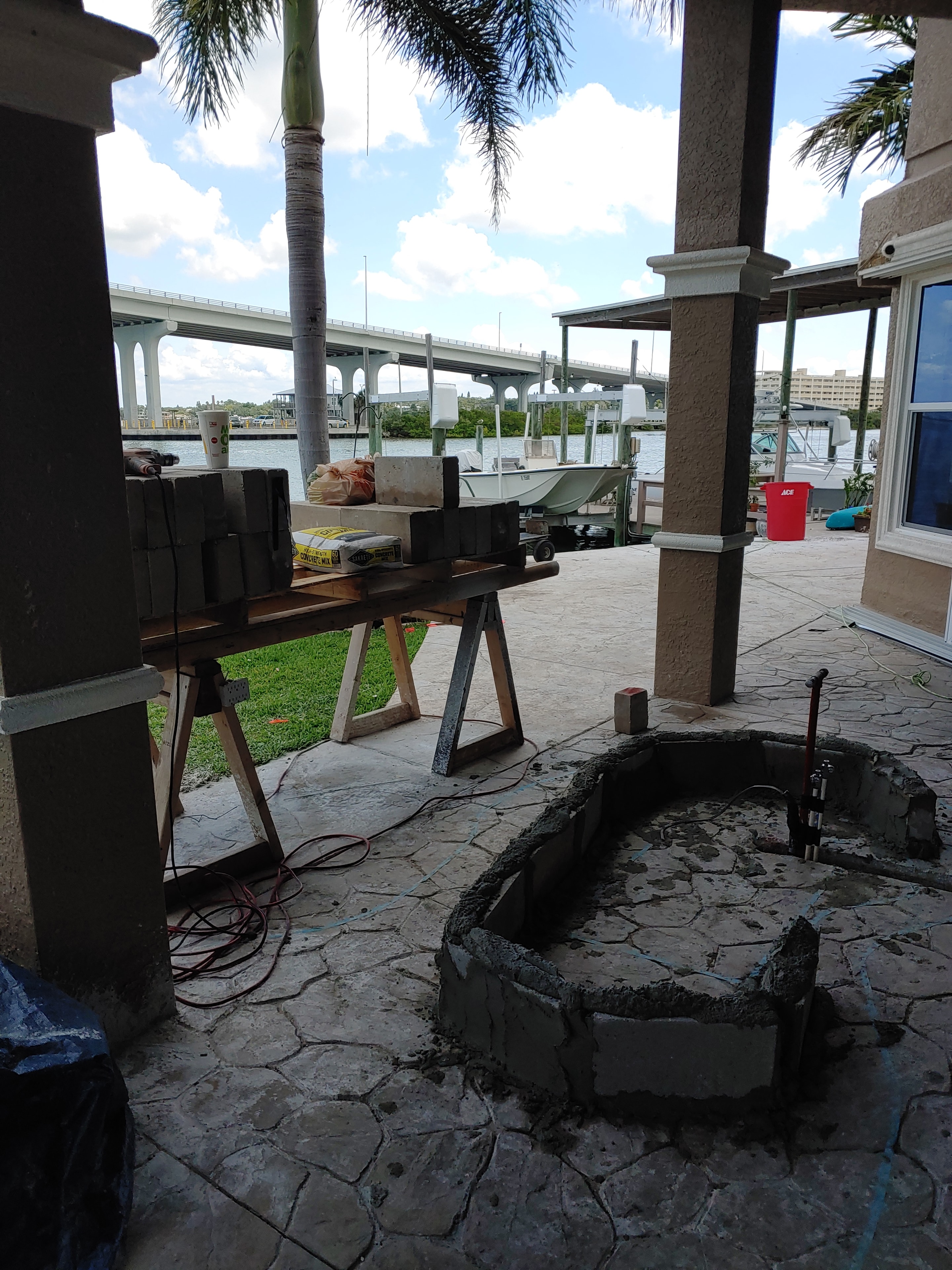 Active waterfront construction site with palm trees and open water views.
